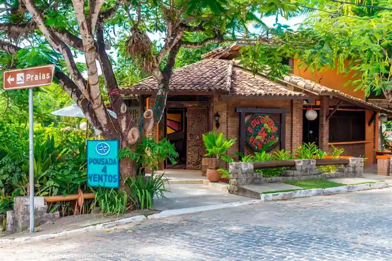Fachada iluminada e jardim planejado da Pousada 4 Ventos, charmosa pousada em Arraial d'Ajuda.