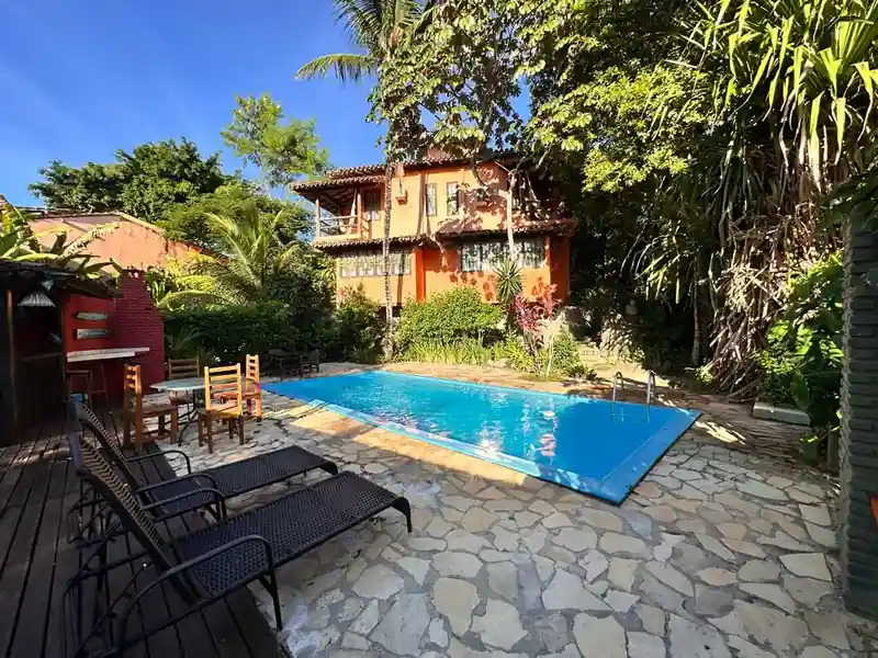 Piscina externa cristalina rodeada por espreguiçadeiras e natureza na Pousada 4 Ventos em Arraial d'Ajuda.